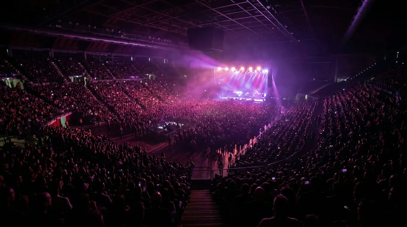 Palasport pieno durante una data di un tour nazionale, pubblico e luci magenta dal palco